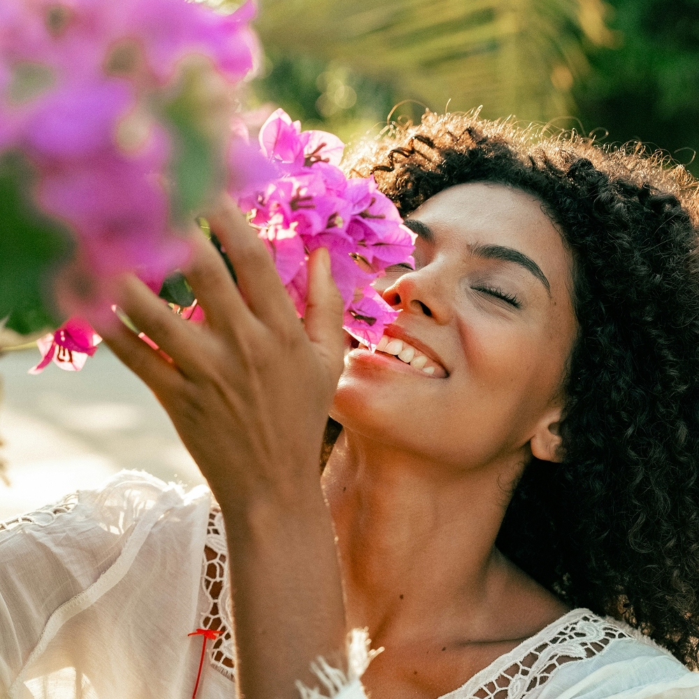 Woman energized by refreshing scent and smiling happily.